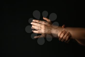 Hands of woman suffering from Parkinson syndrome on dark background�