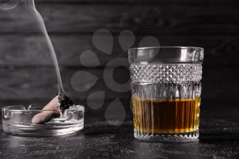 Glass of alcohol and cigar on table. Concept of bad habits�