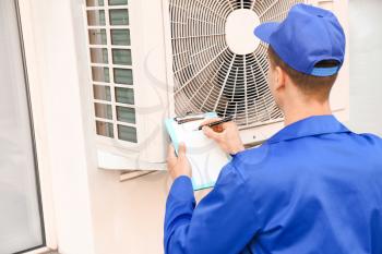 Male technician installing outdoor unit of air conditioner�