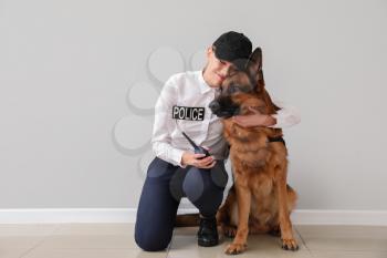 Female police officer with dog near light wall�