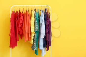 Rack with modern clothes near color wall�