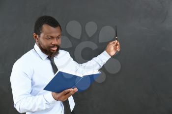 African-American teacher pointing at blackboard in classroom�