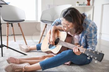Private music teacher giving guitar lessons to little girl at home�