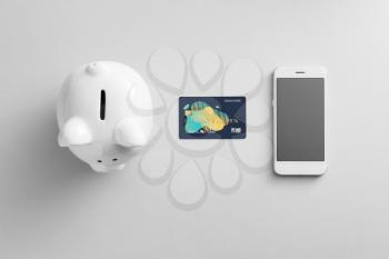 Credit card with mobile phone and piggy bank on white background. Concept of online banking�