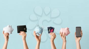 Female hands with piggy banks, credit cards, wallet and mobile phone on color background. Concept of online banking�