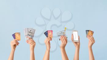 Female hands with money, credit cards, shopping cart and mobile phone on color background. Concept of online banking�