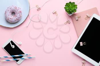 Tablet computer with mobile phone, stationery and doughnut on pink background�