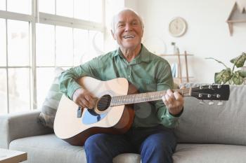 Elderly man playing guitar at home�