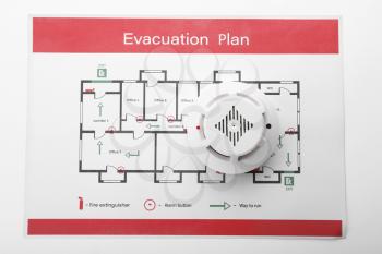 Evacuation plan and smoke detector on white background�