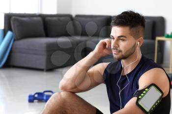 Sporty young man listening to music at home�