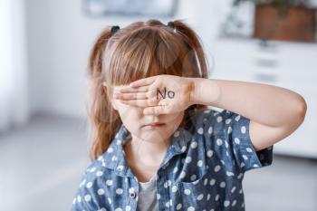 Little girl with word NO on her palm at home. Concept of violence�