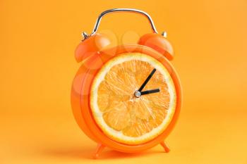 Creative alarm clock with citrus fruit on color background�