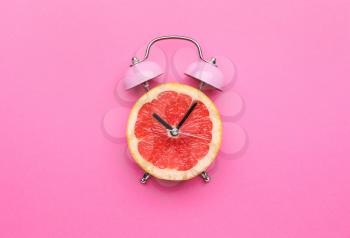 Creative alarm clock made of citrus fruit on color background�