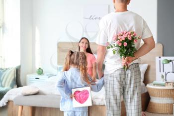 Husband and little daughter greeting woman to Mother's Day in bedroom�