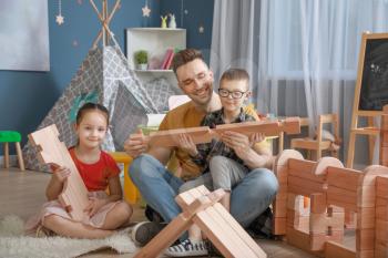 Father and little children playing with take-apart house at home�