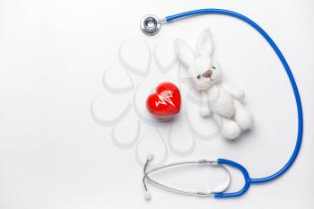 Stethoscope, heart and baby toy on light background�