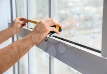 Male worker installing window in flat, closeup�