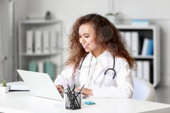 Young African-American doctor working on laptop in clinic�