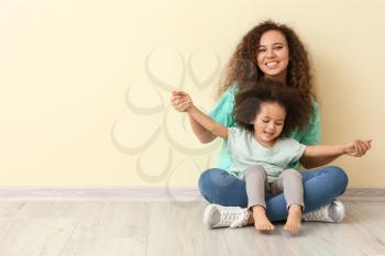 Little African-American girl with her mother near color wall�