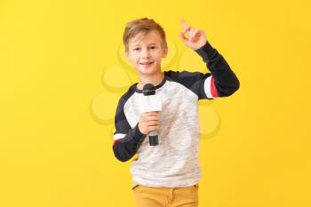 Little journalist with microphone on color background�