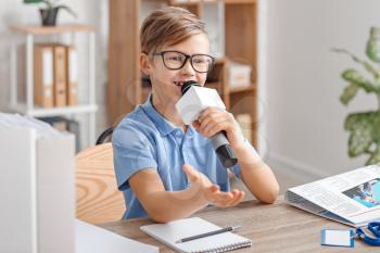 Little journalist with microphone having an interview in office�