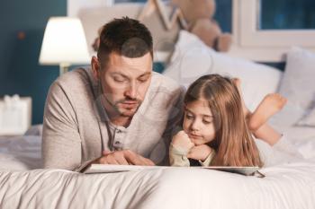 Father and his little daughter reading bedtime story at home�