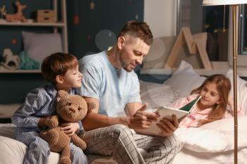 Father and his little children reading bedtime story at home�