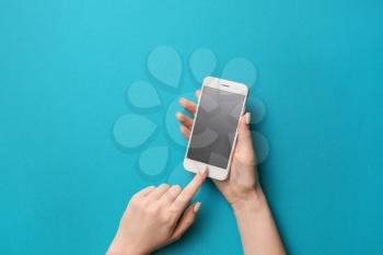 Female hands with mobile phone on color background�