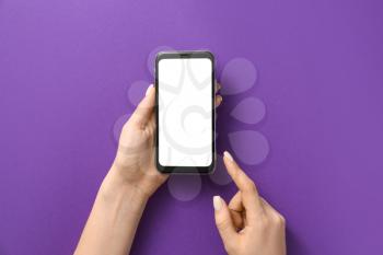 Female hands with mobile phone on color background�