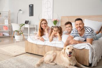 Happy family with dog in bedroom at home�