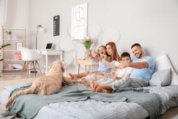 Happy family taking selfie in bedroom at home�