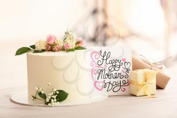Tasty cake with greeting card and gifts for mother on table�