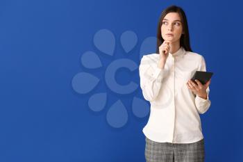 Thoughtful young woman with calculator on color background�