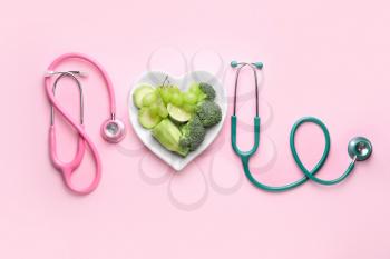 Plate with healthy products and stethoscopes on color background�