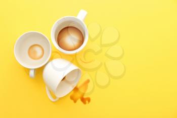 Empty cups and spilled coffee on color background�