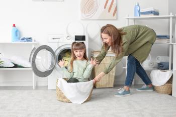 Woman and her cute little daughter having fun while doing laundry at home�
