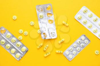 Blister packs and pills with different drawn faces on color background�