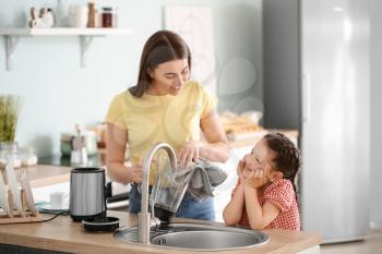 Mother and little daughter cleaning blender in kitchen�