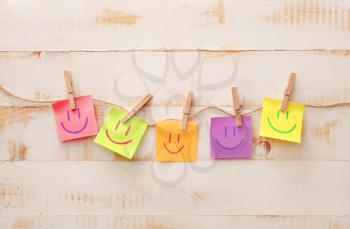 Papers with drawn happy faces on white wooden background�