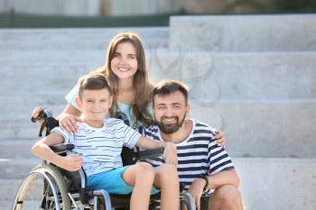 Teenage boy in wheelchair with his family outdoors�