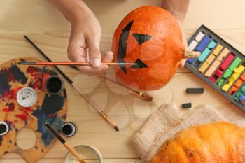 Woman painting pumpkin for Halloween party on wooden table�