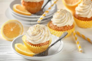 Plate with delicious lemon cupcake on white table�