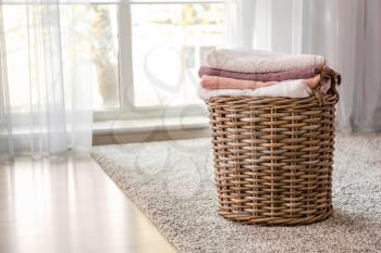 Wicker basket with folded clean towels on floor�