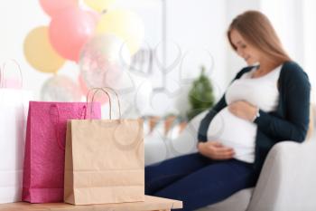 Beautiful pregnant woman with gifts for baby shower party at home�