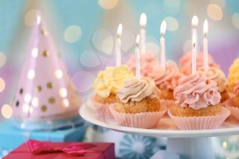 Stand with delicious birthday cupcakes on table�