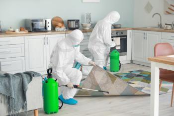 Workers in biohazard suits disinfecting house�