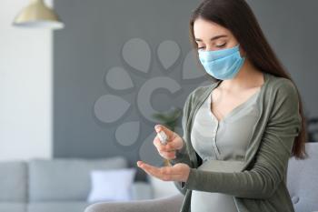 Pregnant woman using sanitizer at home. Concept of epidemic�