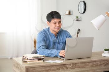 Young Asian man working on laptop at home�