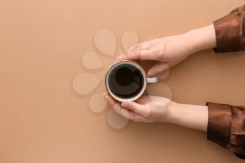 Female hands with cup of hot coffee on color background, top view�