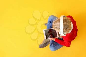 Cute little girl with tablet computer on color background. Concept of online education�